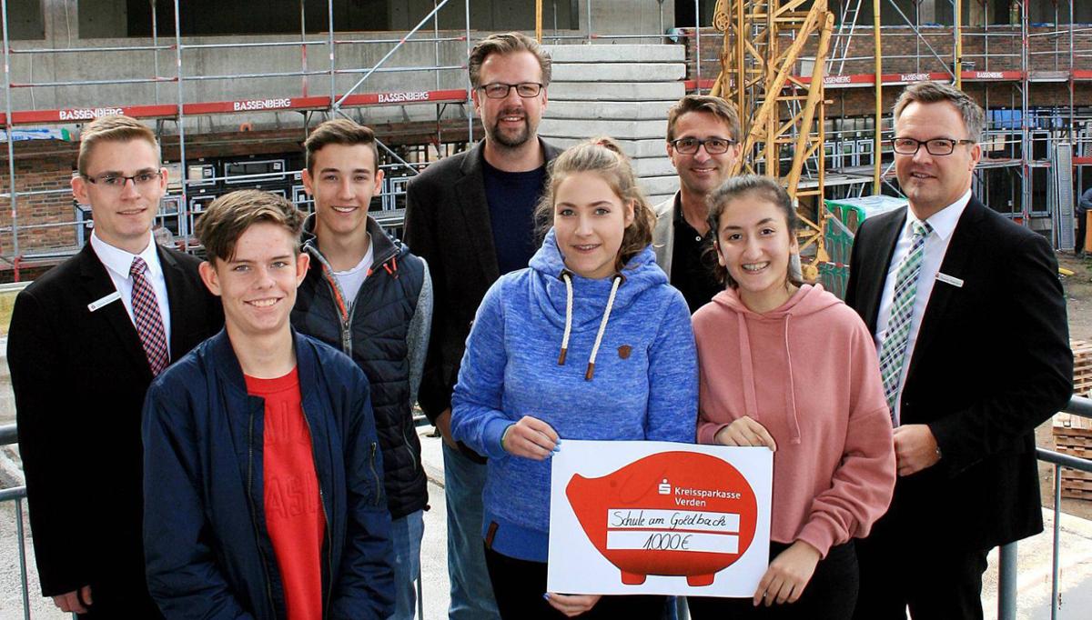 Calvin Dieckhoff (KSK), Niklas Speck, Leon Ksoll, Derik Eicke, Nina Buschmann, Rolf Bartels, Dilara Ersu und Thomas Baeslack (KSK) (v.li.) vor der Baustelle der neuen Oberschule.